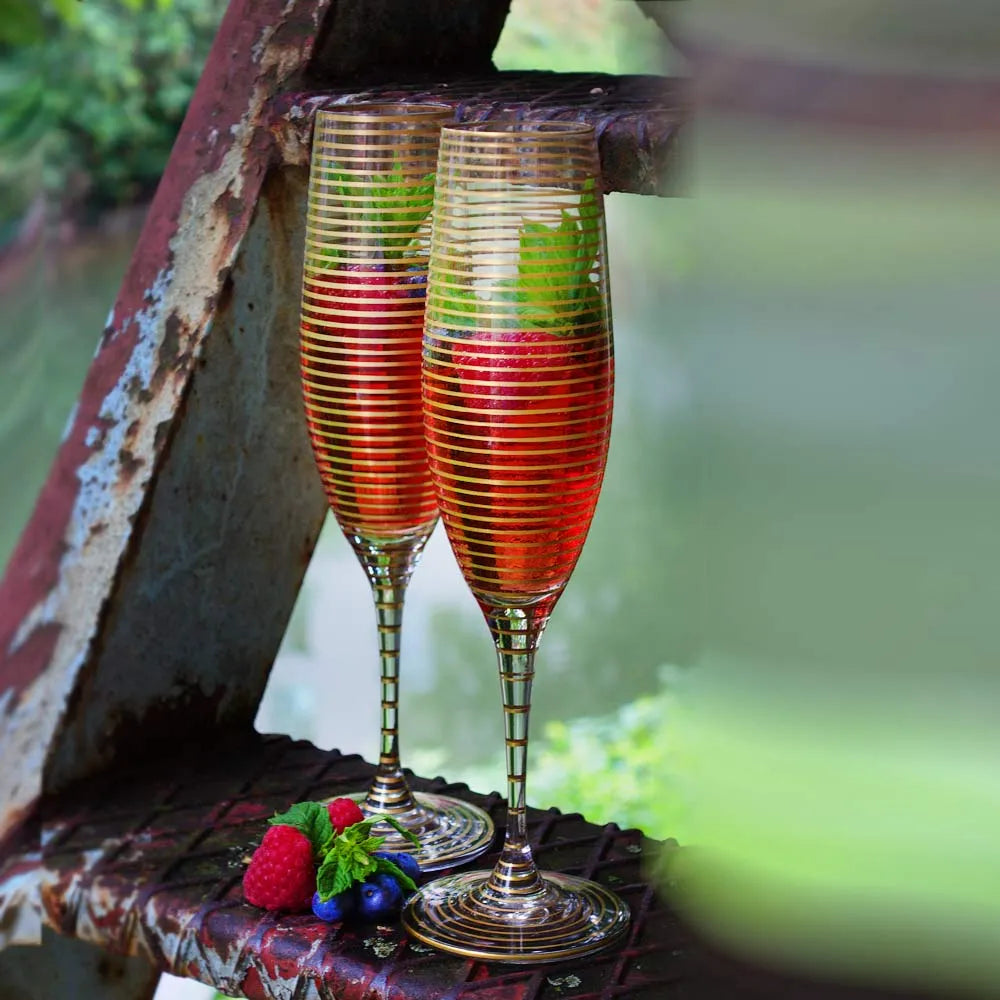 2 Sektgläser mit Gldinien uns rotem Getränk und Himbeeren