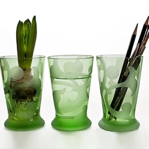 drei grüne Gläser, eines mit Stiften, eines mit Wasser, eines mit Hyazinthe